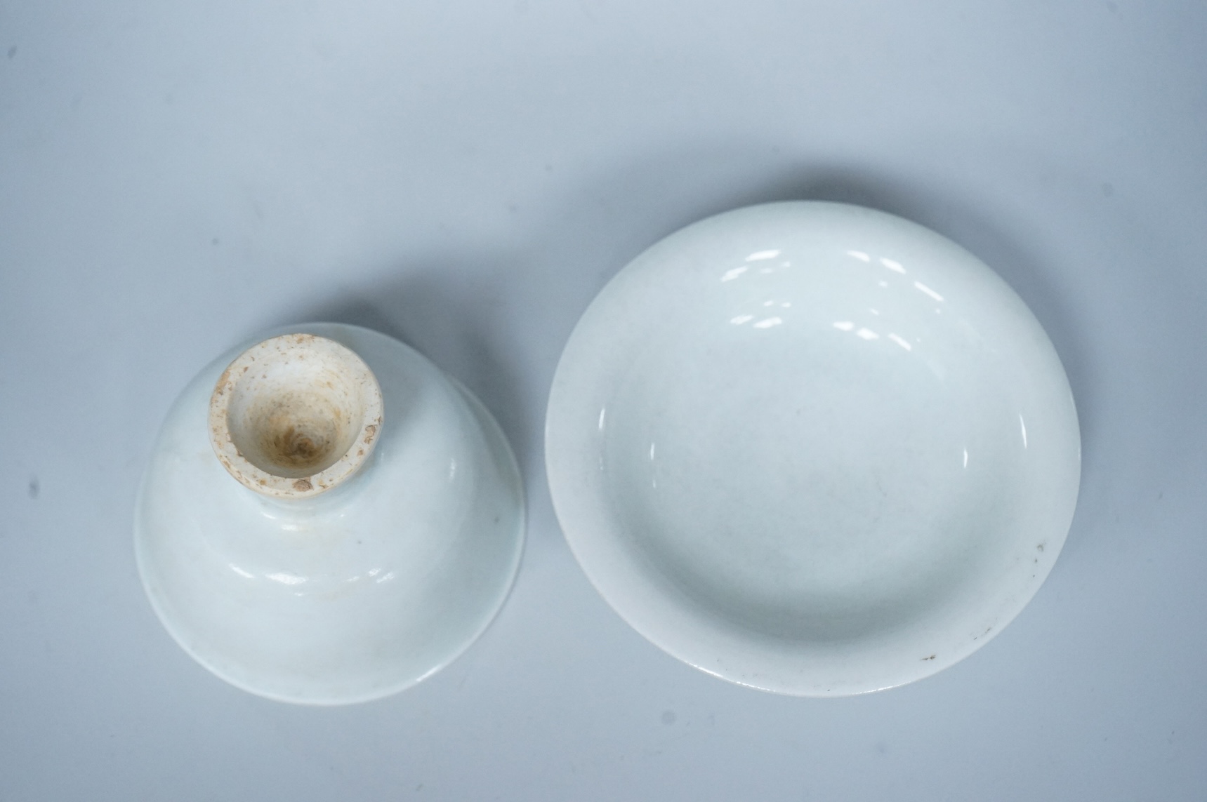 A Chinese white glazed stem cup and similar dish, tallest 7cm